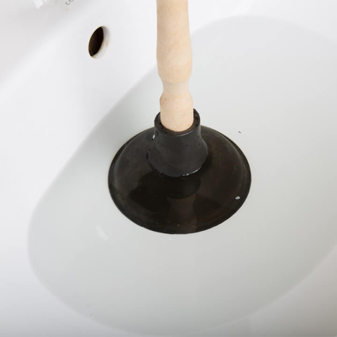 Plunger being used to clear a clogged sink