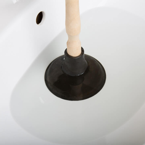Plunger being used to clear a clogged sink drain