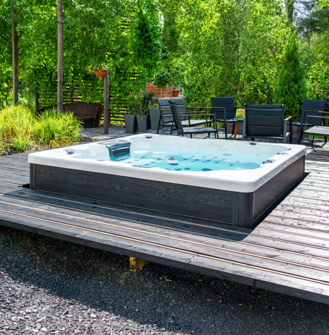 Hot tub set into a deck in a back yard on a bright sunny day