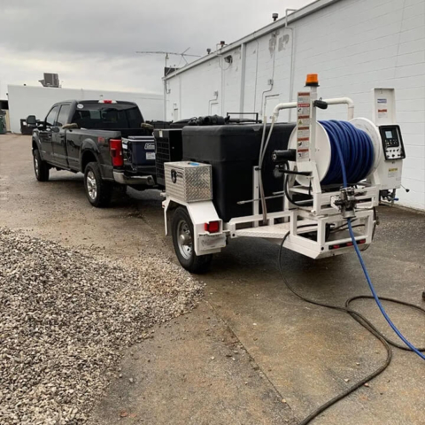 A heavy-duty, trailer-mounted hydro-jetting machine parked outside a facility, ready to provide high-pressure drain cleaning services.
