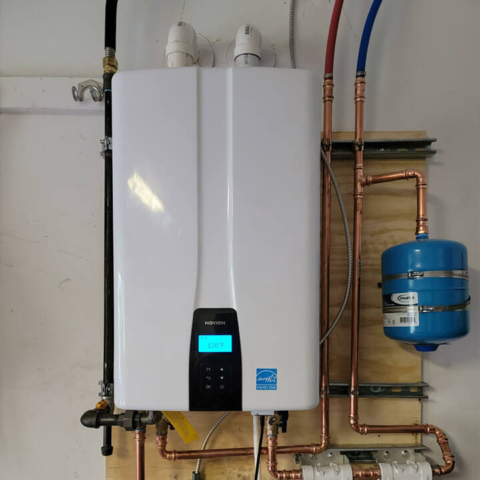 A professional installation of a white tankless water heater with copper piping and a blue expansion tank, showcasing expert residential plumbing services.