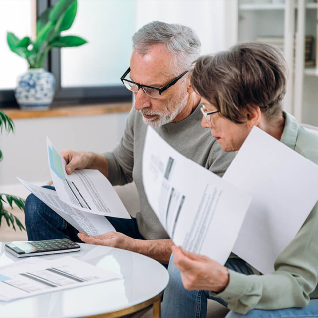 A couple looking concerned while reviewing high utility bills, often a sign of hidden plumbing leaks that require professional leak detection services.
